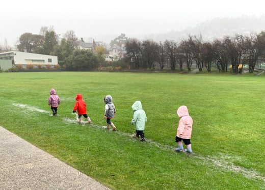 Early Leaning Children playing in Puddles in Raincoats